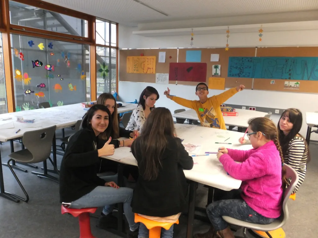 Kinder und Jugendliche basteln an Tischen im Klassenraum.